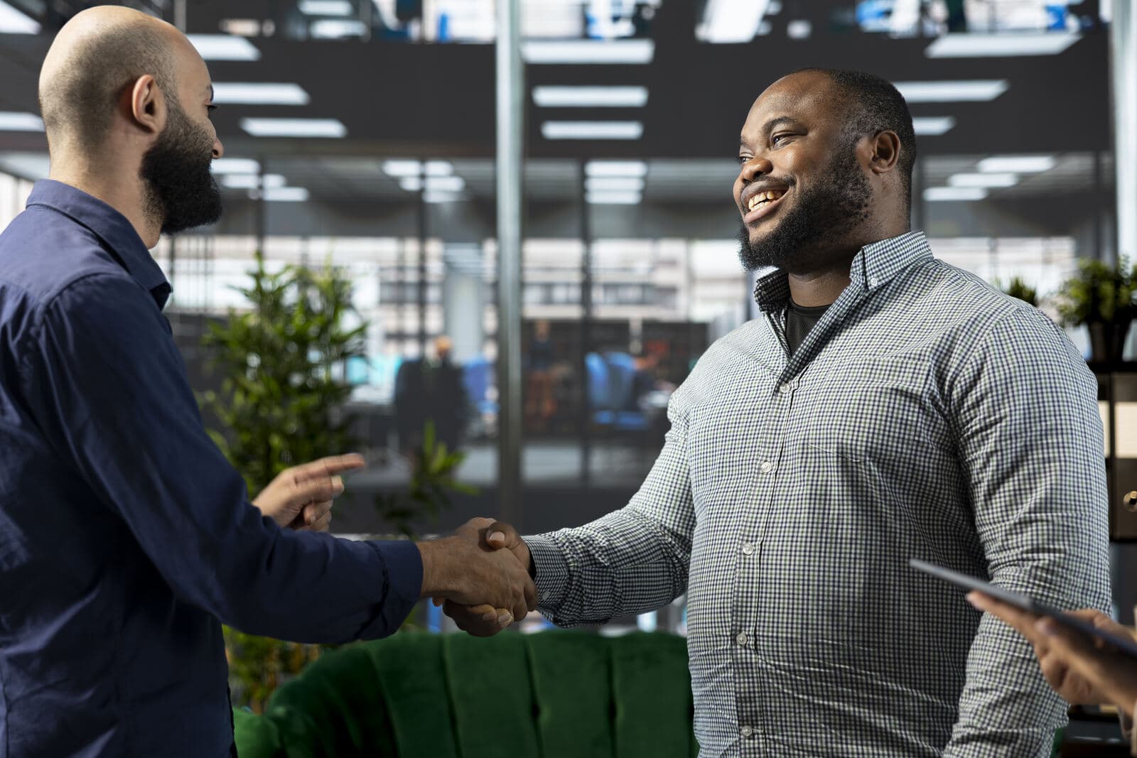 Two men shaking hands and smiling in a bright office